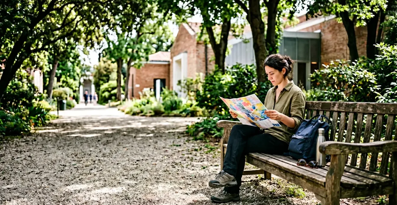 Visitatore che studia una mappa della Biennale di Venezia seduto su una panchina all'ombra dei Giardini