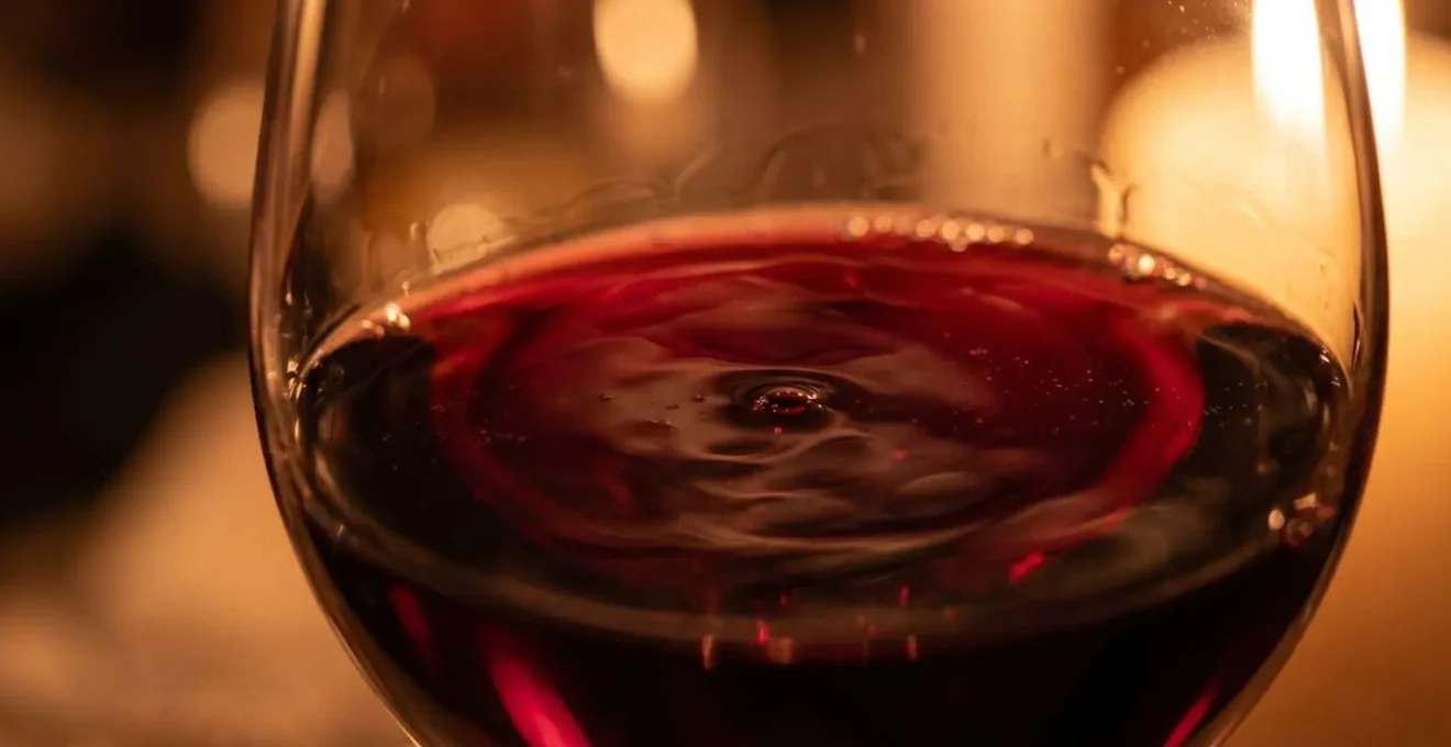 Calice di vino rosso su tavola elegante con riflessi dorati